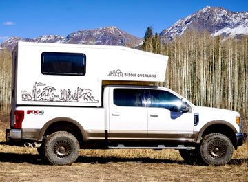 white truck camper with mountain and tree